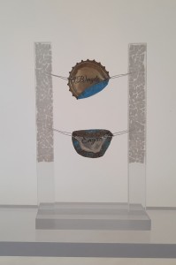 "Mini-Installation" | 2023<br />
Kronkorken-Engelobjekt (Rückseite)<br />
Hühnereischale auf Acrylglas 